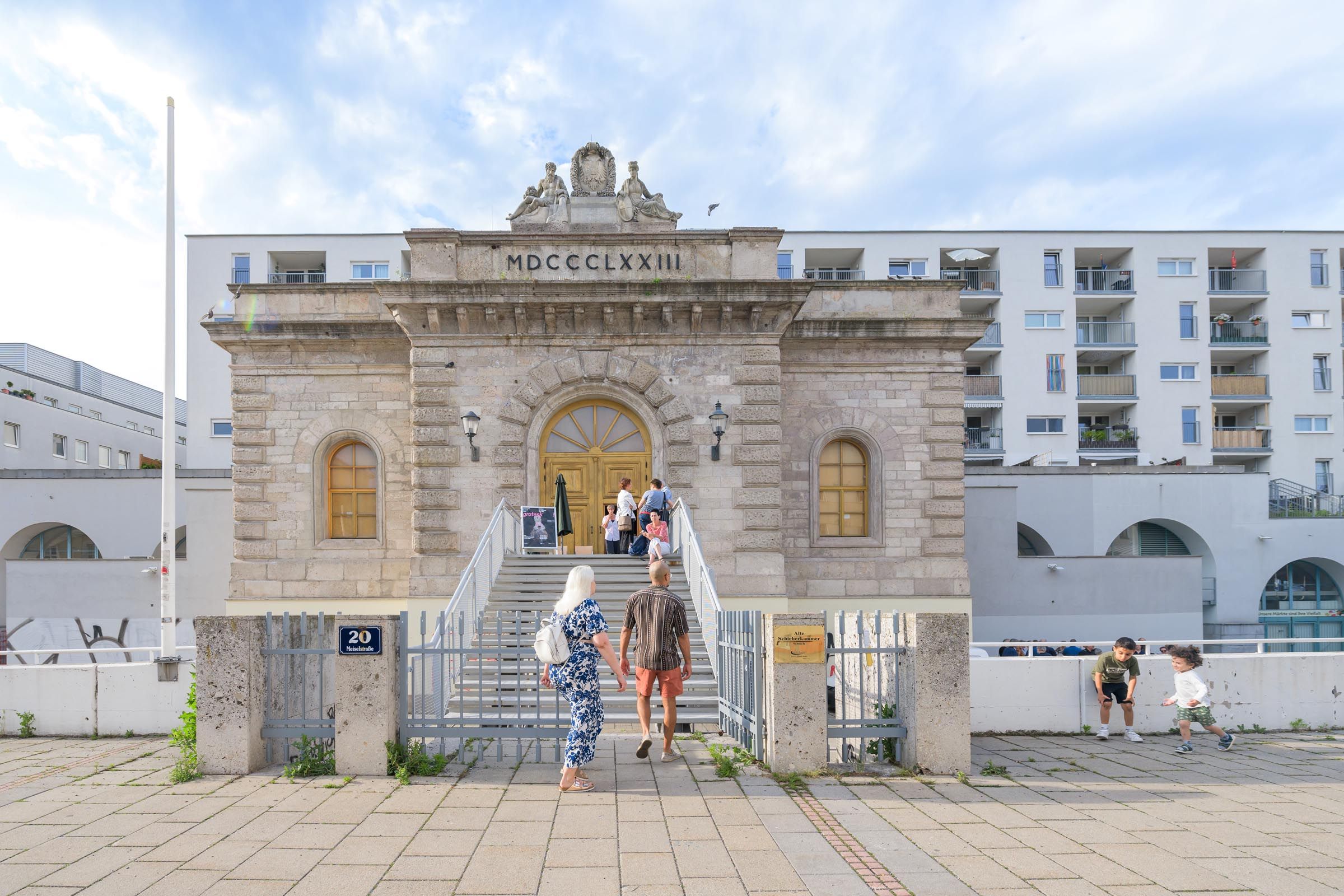 Historisches Gebäude mit imposanter Fassade mit Treppenaufgang vor Neubauten
