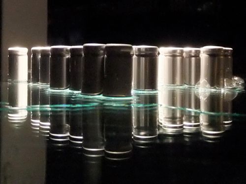 Zylindrische Objekte auf spiegelndem Untergrund sowie auf schwarzem Hintergrund
