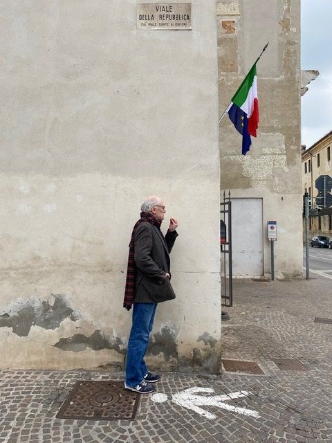 Mann vor einer Wand von einem Gebäude mit Flaggen