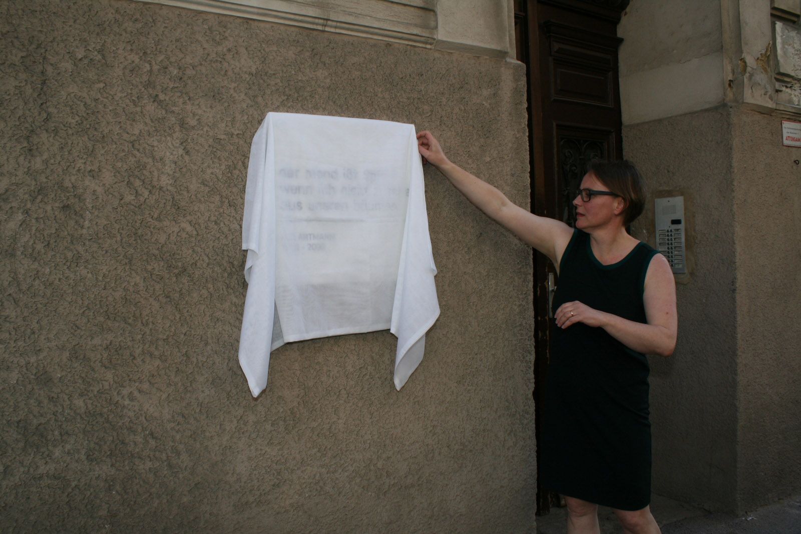Ulrike Tauss vor der verhüllten H. C. Artmann in der Kienmayergasse 43 in Wien Gedenktafel